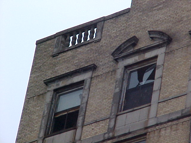 Two window on the upper corner of a building blown out.